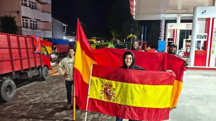 PAWAI BOLA - Sejumlah pemuda fans timnas Spanyol saat ditemui TribunAmbon.com di SPBU Pohon Pule usai pawai membawa bendera seukuran 5 meter mengelilingi pusat Kota Ambon, Selasa (16/6/2026).