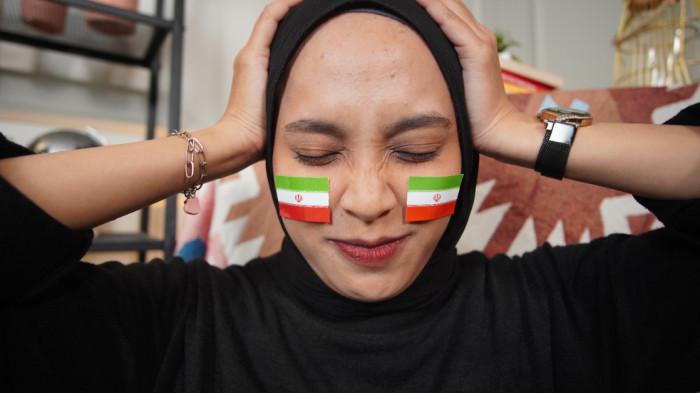 Wanita asal Solo mengenakan stiker Iran di wajah sebagai bentuk dukungan dalam Piala Dunia 2026, di Kota Solo, Jawa Tengah, Senin (15/6/2026).(Tribun-Video.com/Akmal Khoirul Habib)