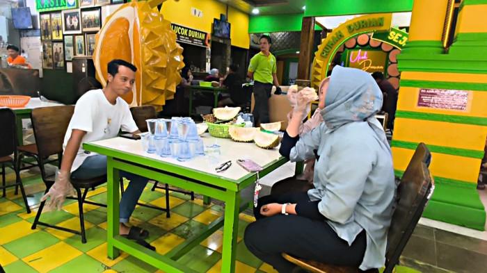 Pengunjung menikmati durian di Kedai Ucok Durian Medan, Jumat (26/12/2025).