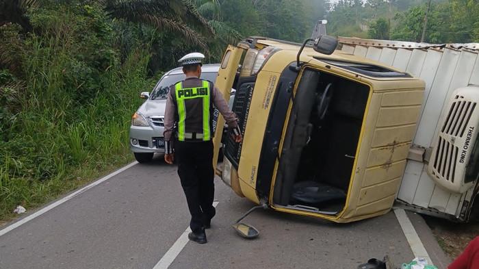 TERGULING - Petugas kepolisian melakukan olah tempat kejadian perkara truk boks berisi froozen food terguling di Jalan Ness Jambi-Muara Bulian, Senin (22/6/2026) pagi. Satu orang mengalami luka akibat insiden itu.