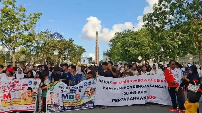 SISWA DUKUNG MBG - Sejumlah siswa SMP, SD dan guru menggelar demonstrasi mendukung program andalan Presiden Prabowo Subianto, Makan Bergizi Gratis (MBG) di depan Kantor Wali Kota dan DPRD Kota Batam, pada Minggu (21/6/2026). Aksi diduga diarahakan pihak sekolah dan Dinas Pendidikan Batam namun dibantah. Orangtua siswa terkejut semula dikira acara pawai dari sekolah