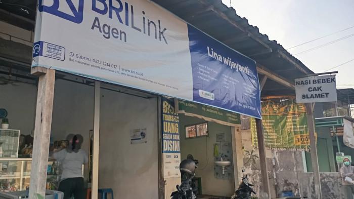 AKSES FINANSIAL DEKAT RUMAH — Eksterior kios kelontong sekaligus Agen BRILink milik Lina Wijayanti yang terletak di Jalan Kenanga, Keboansikep, Gedangan, Sidoarjo, Jawa Timur. Keberadaan papan nama keagenan resmi ini sangat mempermudah warga desa mengenali lokasi transaksi keuangan terdekat untuk melakukan penarikan saldo, transfer, hingga pembayaran berbagai tagihan secara praktis