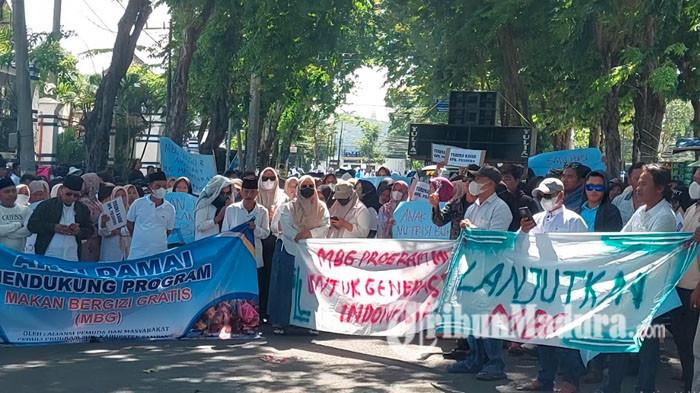 AKSI DAMAI - Masyarakat Sampang, Madura, yang tergabung dalam Aliansi Pemuda dan Masyarakat Peduli Program Makan Bergizi Gratis (MBG) menggelar aksi damai di depan kantor DPRD setempat, Kamis (25/6/2026) siang. Massa datang dari tiga titik kumpul berbeda, yakni Jalan Barisan Indah, Taman Bunga depan Kantor Pemkab Sampang, serta Jalan Wahid Hasyim. 