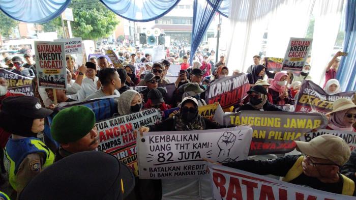 DEMO MANDIRI TASPEN - Ratusan massa yang terdiri dari nasabah, pensiunan, hingga anak cucu korban menggeruduk kantor Bank Mandiri Taspen Purwokerto, Jumat (26/6/2026). Mereka menuntut pihak bank bertanggung jawab atas dugaan kasus penipuan yang menimpa para nasabah serta membatalkan skema kredit yang dinilai merugikan korban.