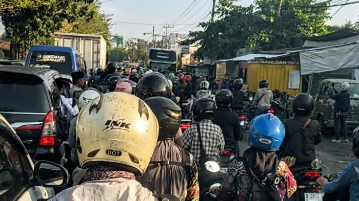 MACET - Penumpukan kendaraan hingga menutup jalur protokol pintu keluar-masuk sisi Timur Kota Bangkalan, Madura, Jawa Timur, terpantau akibat antrean menuju SPBU Junok pada Jumat (26/6/2026). Kondisi tersebut membuat personel Satlantas Polres Bangkalan menerapkan pola tutup, sementara operasional SPBU dihentu=ikan untuk mengurai penumpukan kendaraan.