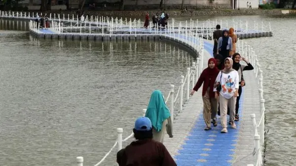 Wisatawan melintas di jembatan apung Situ Rawa Kalong, Depok, Jawa Barat, Sabtu (25/1/2025).  Jembatan apung yang dibangun kolaborasi Pemerintah Provinsi Jawa Barat dan Pemkot Depok tersebut menjadi daya tarik  bagi warga yang berkunjung memanfaatkan libur akhir pekan, serta libur panjang Isra Miraj Nabi Muhammad dan Tahun Baru Imlek. ANTARA FOTO/Yulius Satria Wijaya/Spt.
