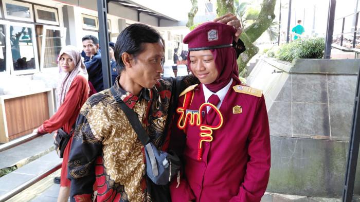 SOLUSI PENDIDIKAN - Darsito tersenyum sembari mengelus kepala putrinya, Nur Mauliza (13), seusai kegiatan open house dan pengambilan rapor kenaikan kelas di Sekolah Rakyat Menengah Pertama (SRMP) 13 Kabupaten Banyumas, Senin (19/6/2026). Di tahun pertama pembukaan, Sekolah Rakyat Banyumas menerima 50 siswa dari keluarga miskin.