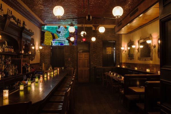 An empty restaurant dining area with tables and a bar warmly lit by overhead lighting and candles Credit: Casey Robinson/Royal Sushi & Izakaya