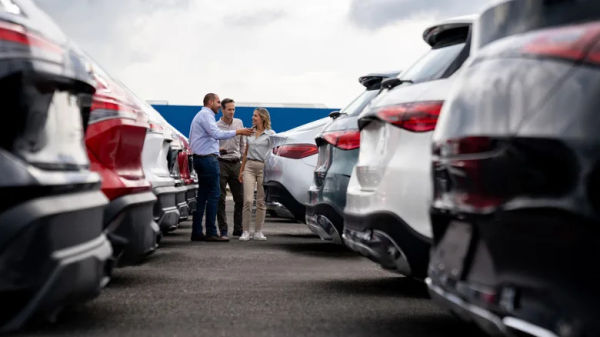 People looking at cars in a dealership.