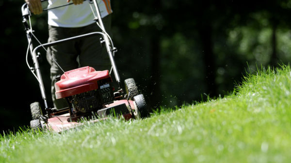 Person mowing grass on an incline