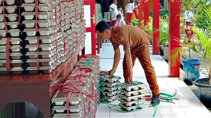 MBG - Seorang guru menata ompreng Makan Bergizi Gratis (MBG) sebuah SD di Kecamatan Sumbersari, Kabupaten Jember. Jawa Timur pada Senin (8/6/2026). Diungkapkan bahwa sejumlah SPPG di Jember berhenti operasional sementara .
