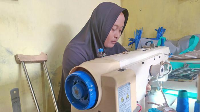 UMKM PRODUSEN TAS - Karyawan perempuan disabilitas yang berkarya di Vita Merchandise, produsen tas di Dusun 2, Desa Purbayan, Kecamatan Baki, Kabupaten Sukoharjo, Jawa Tengah. Keduanya sedang menjahit tas tote bag pesanan pelanggan.