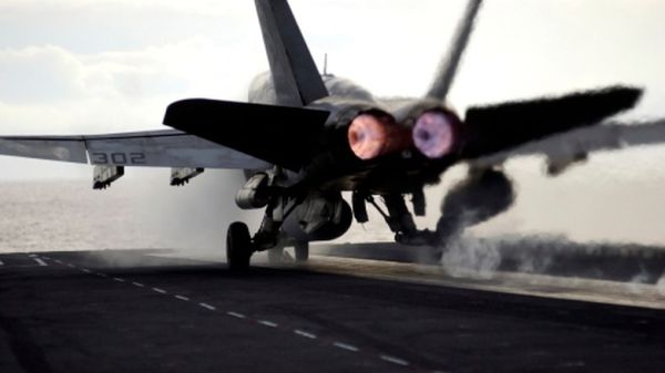 Rear view of F/A-18 Hornet launching from deck of USS Ronald Reagan.