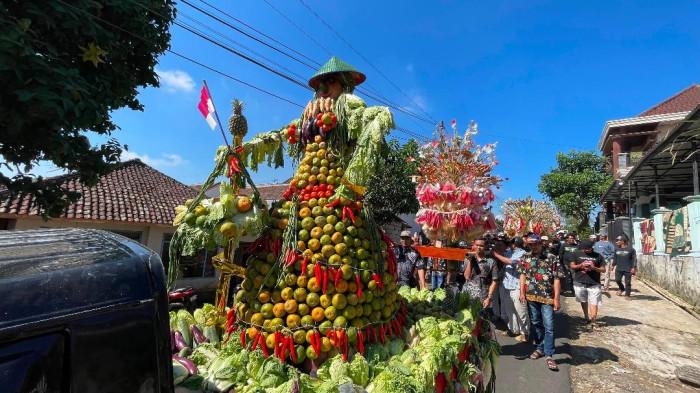 BERSIH DESA - Warga berebut tumpeng gunungan jeruk dan kerupuk opak serta hasil bumi saat acara Bersih Desa di Desa Selorejo, Kecamatan Dau, Kabupaten Malang, Senin (29/6/2026).