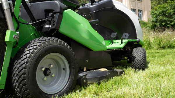 A green riding lawn mower on grass.