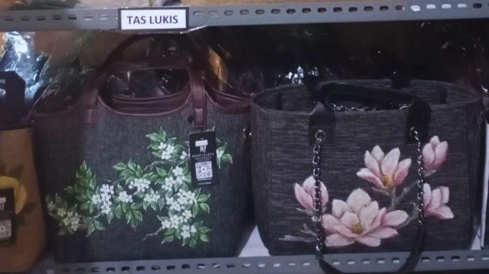 Dua buah produk tas kain bermotif lukisan tangan (handpainted) bunga melati dan magnolia dipajang