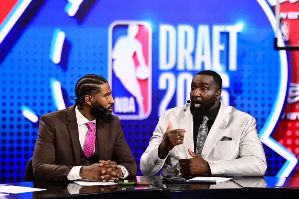 Two male commentators sitting at a desk with an NBA Draft 2026 backdrop.