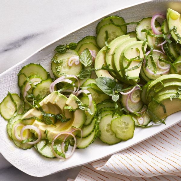 a white platter with cucumbers and avocados