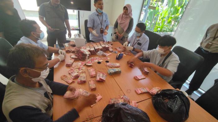 MENGHITUNG - Petugas dari BI Tegal saat melakukan penghitungan uang milik dr Ida yang rusak akibat terendam rob.