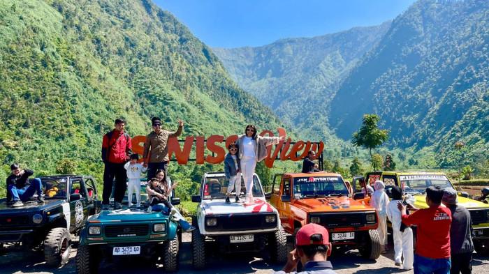 PEMANDANGAN PEGUNUNGAN - Wisatawan berfoto di atas jip dengan latar belakang pegunungan di kawasan Swiss Van Java, Desa Mlandi, Kecamatan Garung, Kabupaten Wonosobo, Jumat (3/7/2026). Swiss Van Java Garung menjadi destinasi wisata baru di Wonosobo.