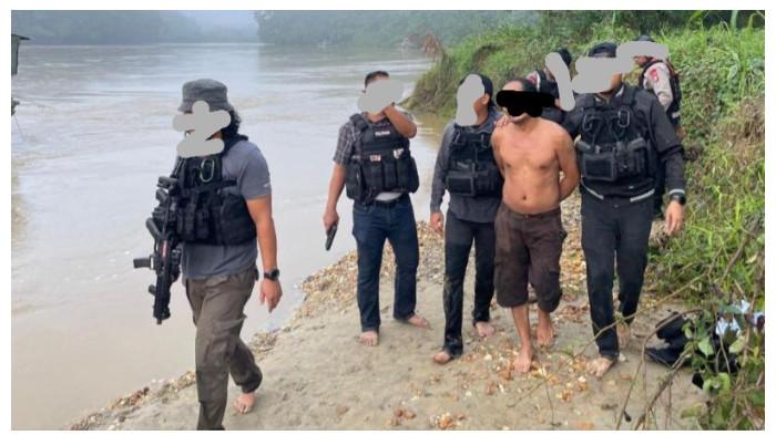 PENANGKAPAN - Satu terduga pelaku tampak dikawal sejumlah personel bersenjata lengkap saat dibawa keluar dari lokasi penangkapan di tepian Sungai Katingan, kawasan Desa Tumbang Pariyei, Kecamatan Katingan Tengah, Jumat (3/7/2026).