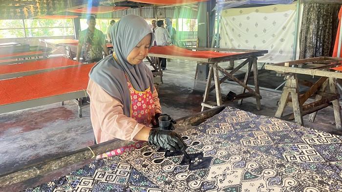 Seorang perajin menunjukkan proses pembuatan batik tulis di Ayu Fashion, Kelantan, Malaysia