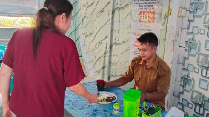 LAYANI PEMBELI - Nasabah PNM Fennawaty Tanuwijaya asal Pa'lambasan, Makassar, Sulawesi Selatan sedang melayani pembeli di tempat jualannya