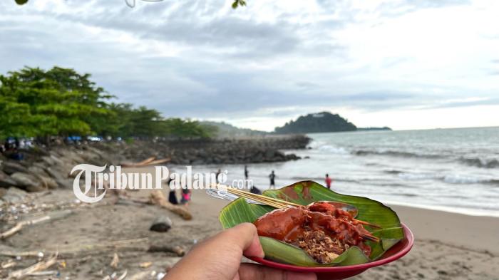 SATE DI TAPLAU- Senja di Pantai Padang selalu punya cara sendiri memanggil orang datang. Bukan hanya lewat warna langitnya, tetapi juga melalui aroma sate padang yang mengepul dari kuali-kuali panas di tepi laut, menyatu dengan debur ombak dan hiruk-pikuk Taplau.