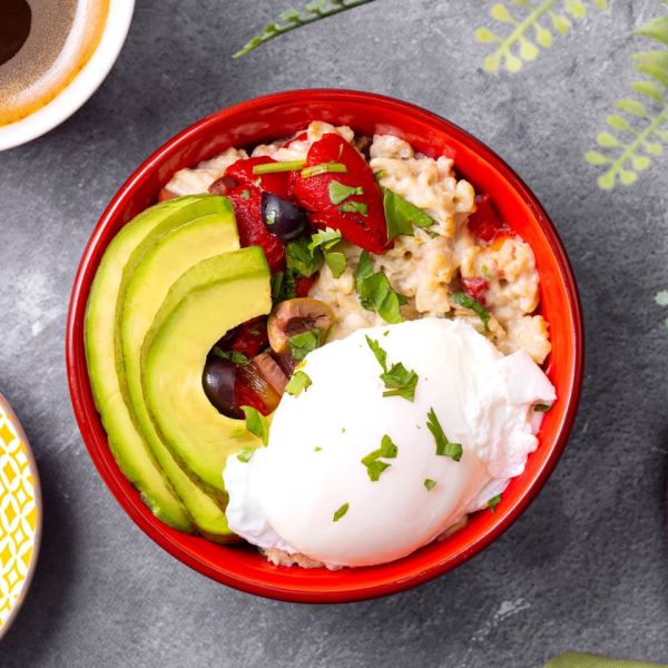 Savory oatmeal bowl with avocado slices poached egg and toppings in a red bowl Credit: Abbey Littlejohn