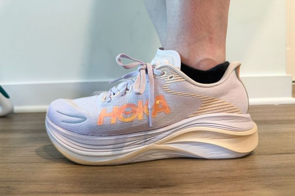 Side view of a Hoka running shoe on a persons foot displaying the shoes profile and branding Credit: EatingWell