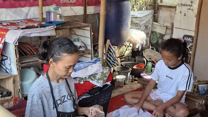 SAMBIL BELAJAR: Zeezee (kanan) saat mendampingi ibunya sembari membaca buku pelajaran di warung. Zeezee diterima masuk ke Sekolah Rakyat DIY dan akan mulai tinggal di sana pada 13 Juli nanti.