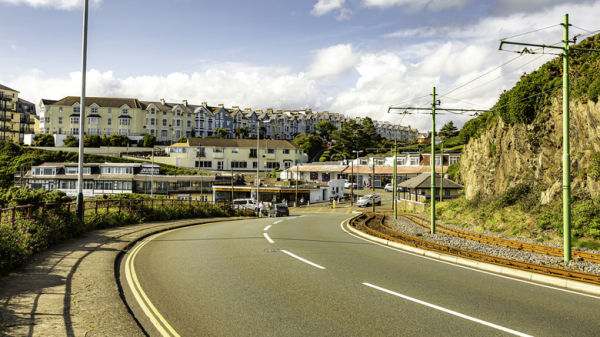 Winding road on the Isle of Man with houses and apartments in the distance.