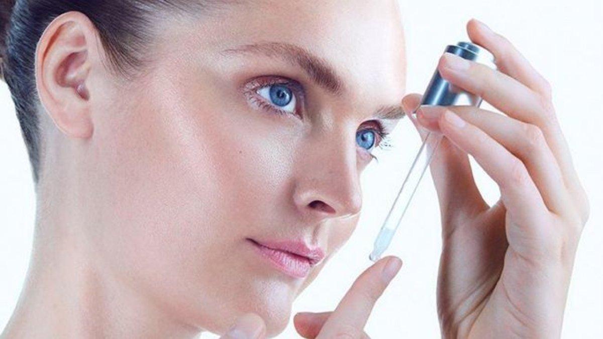 Ilustrasi wanita menggunakan serum wajah.