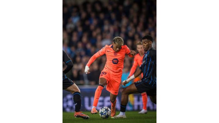 Pemain Barcelona, Lamine Yamal sedang menggiring bola melewati beberapa pemain Club Brugge.