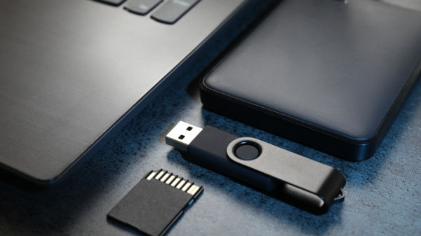 Portable Hard Drive, Thumb Drive, and Memory card next to a laptop