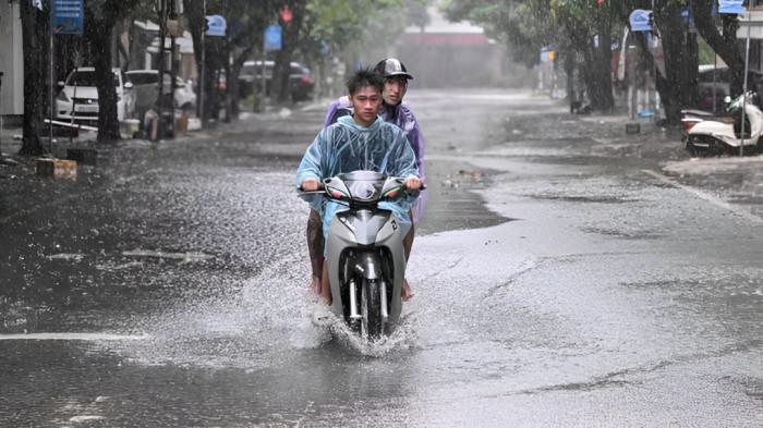 MENEMBUS GENANGAN AIR- Pengendara motor tampak kebasahan diguyur hujan berusaha menembus genangan air yang merendam jalanan perkotaan.