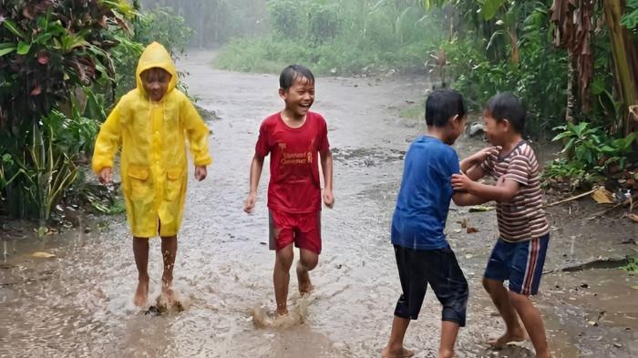 BASAH KUYUP- Empat orang anak tampak basah kuyup saat mandi hujan di sekitar tempat tinggal mereka. Menurut BMKG, pada Senin 20 Juli 2026, wilayah Sumatera Utara masih berpotensi dilanda hujan ringan.