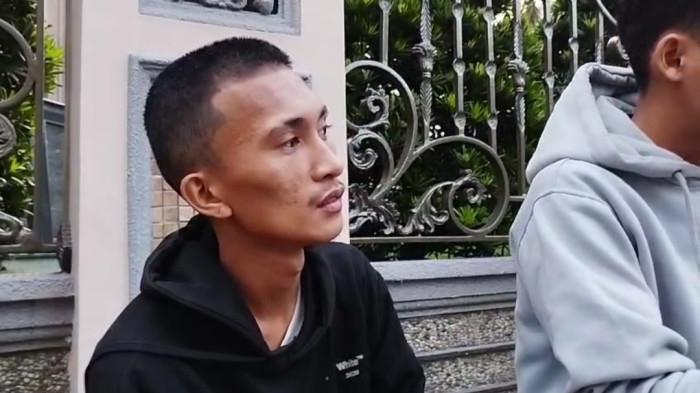 LEDAKAN RUMAH MEWAH - Hendry, abang kandung salah satu korban ledakan rumah mewah di Komplek Grand Polonia, Kecamatan Medan Polonia, menatap lirih ke dalam komplek tempat adiknya bekerja, Selasa (21/7/2026). Pria yang mengenakan sweater berwarna hitam ini mengaku, terakhir kali berkomunikasi dengan sang adik kemarin siang.