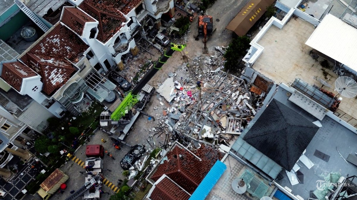 Petugas mengoperasikan alat berat untuk membersihkan puing-puing rumah yang terdampak pascaledakan di Komplek Grand Polonia, Medan, Selasa (21/7/2026). Berdasarkan hasil penyelidikan awal Polrestabes Medan, ledakan tersebut diduga dipicu kebocoran pipa gas bawah tanah yang mengakibatkan tujuh rumah mengalami kerusakan. (TRIBUN MEDAN/DANIL SIREGAR)