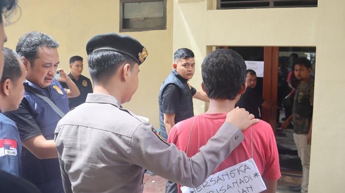 REKONSTRUKSI - TS alias Trisanadi Setiawan (27) digiring petugas saat memeragakan adegan yang menyebabkan nyawa Zulkifli (42) terenggut pada akhir tahun lalu. Rekonstruksi ini digelar di Mapolres Bungo, Senin (11/5/2026). Kini, perkara pembunuhan tengah malam itu memasuki babak baru.