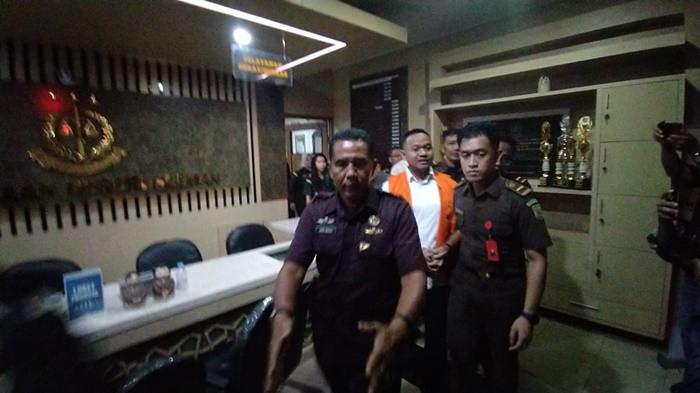 TERSANGKA - Penampakan tersangka baru kasus korupsi dana hibah pariwisata Sleman tahun 2020, Raudi Akmal (RA), mengenakan rompi orange dengan tangan terborgol digiring petugas ke mobil tahanan, Senin (22/6/2026) malam