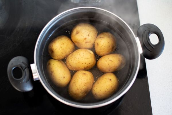 उकळत्या पाण्याने भांडे मध्ये बटाटे
