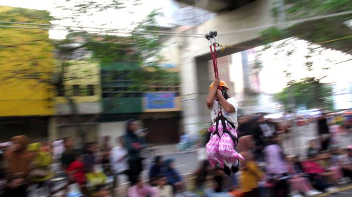 Seorang anak meluncur menggunakan wahana flying fox gratis
