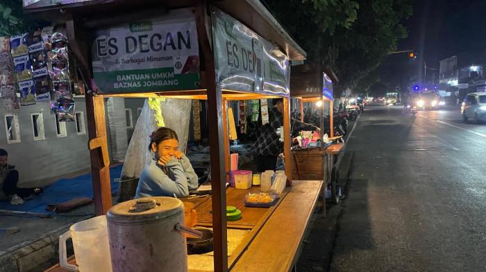 ANGKRINGAN - Potret penjaga warung angkringan di sekitar kawasan Taman Parimono, Kecamatan Jombang, Kabupaten Jombang, Jawa Timur, Sabtu (25/7/2026). Tetap bertahan meski bekerja di balik Stigma buruk