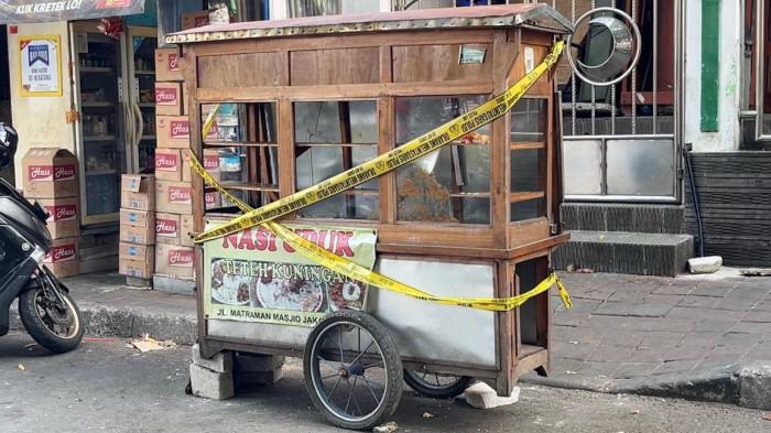 BENTROKAN - Petugas kepolisian melakukan olah TKP di lokasi bentrokan di Jalan Tambak, Menteng, Jakarta Pusat, Minggu (26/7/2026). Gerobak nasi uduk yang disebut menjadi lokasi awal keributan juga telah dipasangi garis polisi. Tampak gerobak itu berwarna cokelat dan ada spanduk kecil di dekat ban bertuliskan 