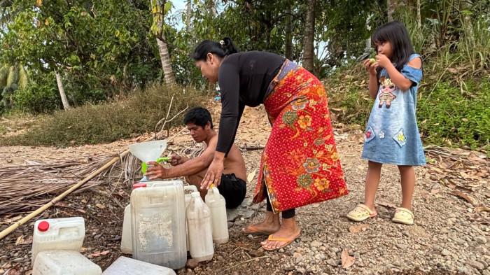 KEKURANGAN AIR - Warga menimba air dari sebuah sumur kecil ke jeriken yang mereka bawa