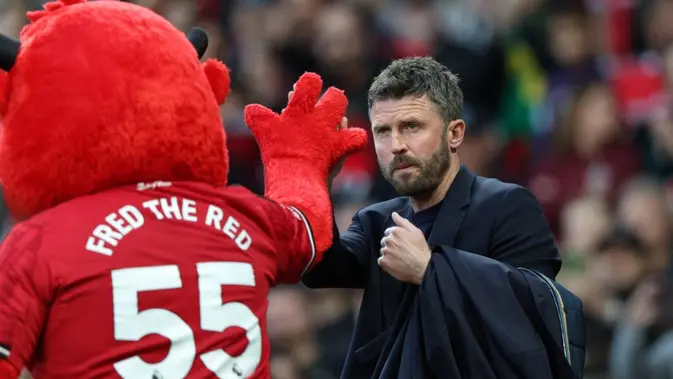 Pelatih sementara Manchester United asal Inggris, Michael Carrick (kanan), bertepuk tangan dengan maskot Fred the Red menjelang dimulainya pertandingan Liga Inggris antara Manchester United dan Brentford di Old Trafford, Manchester, barat laut Inggris, pada 28 April 2026. (Darren Staples/AFP)