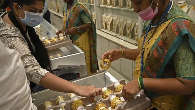 Seorang pelanggan (kiri) memeriksa gelang emas selama festival Hindu 'Akshaya Tritiya', hari keberuntungan dalam kalender Hindu untuk membeli barang-barang berharga, di ruang pamer perhiasan di Chennai, India. Membeli emas adalah kegiatan yang populer di Akshaya Tritiya, karena ini adalah simbol utama kekayaan dan kemakmuran. (Arun SANKAR / AFP)