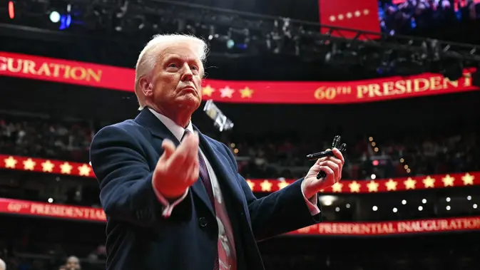 Presiden AS, Donald Trump melemparkan pena ke arah kerumunan setelah menandatangani perintah eksekutif selama parade perdana di dalam Capital One Arena, Washington, DC. (Jim WATSON/AFP)
