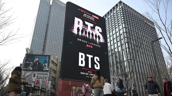 Orang-orang berjalan melewati papan reklame yang mempromosikan konser comeback grup K-pop BTS di Lapangan Gwanghwamun di Seoul pada 17 Maret 2026. (dok. Jung Yeon-je / AFP)